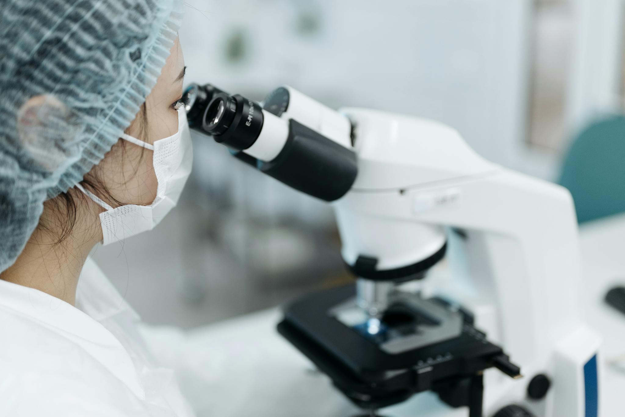 Female scientist examining samples using a modern microscope in a research lab.